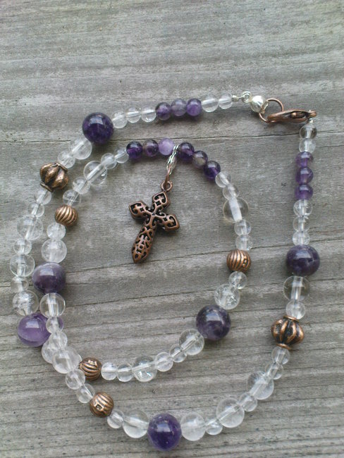Kette aus Amethyst und Bergkristall mit kupfernem Kreuzanhänger und Perlen.