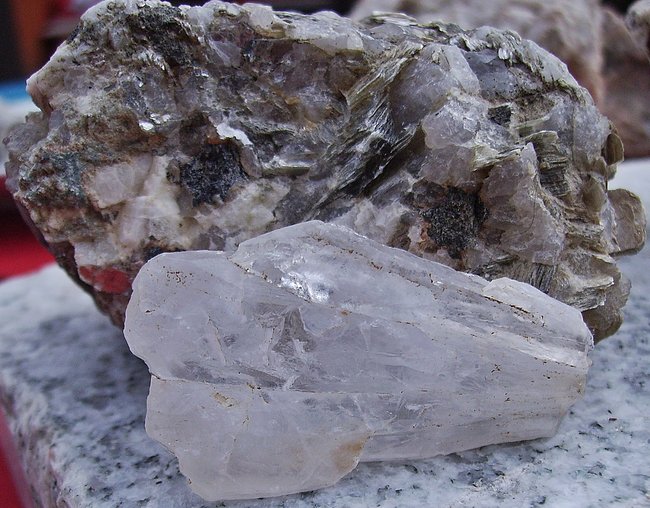 Stück grosser Sternquarz, dahinter Rätselstein, vermutlich  Randgranit mit viel Muskovit + evtl. Turmalin