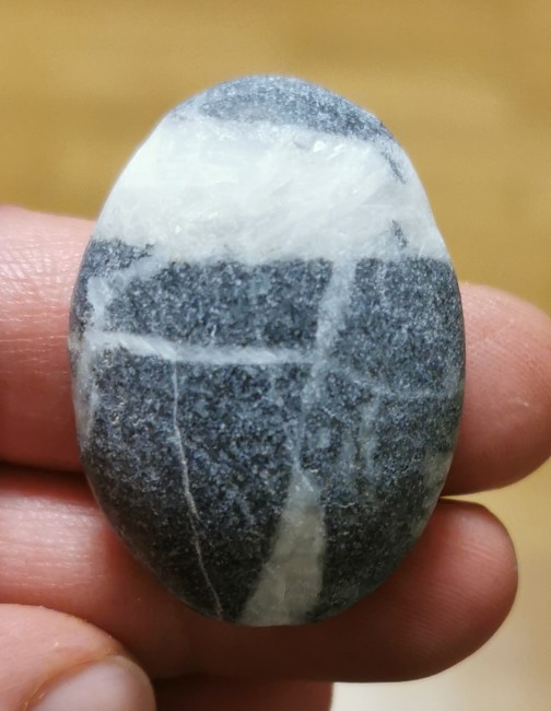 Vermutlich Granit mit Quarzadern . Oben rechts will die Form einfach nicht bestehen bleiben. Durch den weichen Schaumstoff Untergrund von der Schleifscheibe verformt sich der Stein hier jedes mal. Nach dem dritten Versuch, ihn in Form zu bringen habe ich es aufgegeben. Auf dem Bild sieht es weniger stark aus, als es in Wirklichkeit ist.